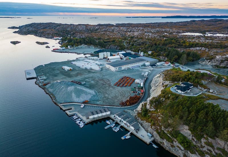 Flyfoto av Ølen Betong's samferdselsfabrikk i Sveio. Store lagerarealer utenfor med en småbåthavn som nærmeste nabo.